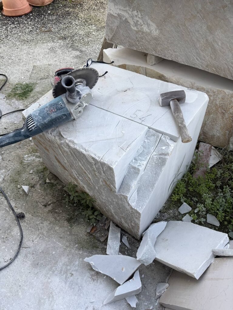 Marble block after the first cuts and hammer work, white flakes on the workshop floor